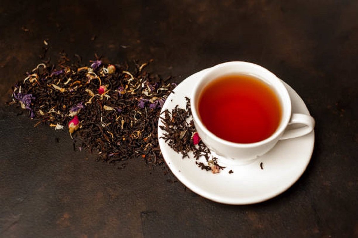 tasty tea in a white mug, scattered tea on a stone background